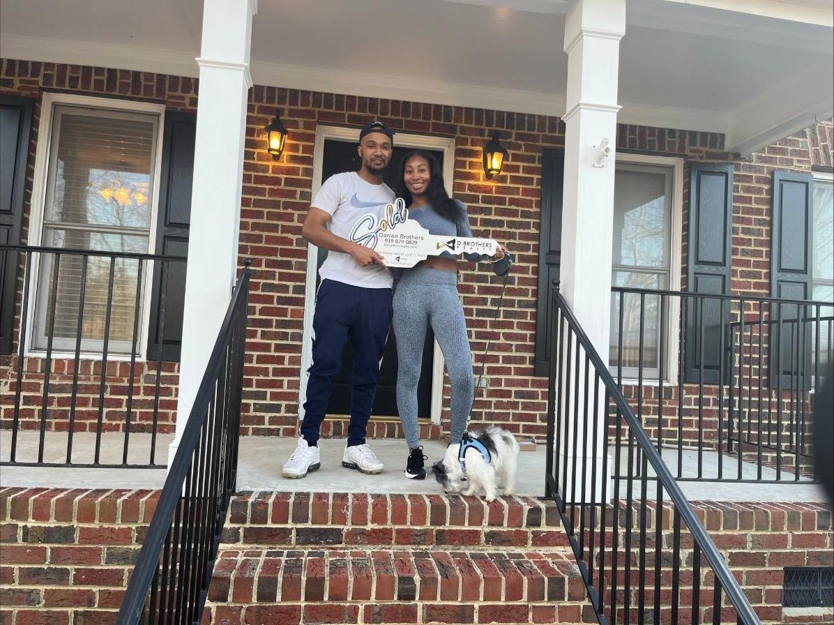 Clients on the porch of their new home with their SOLD key